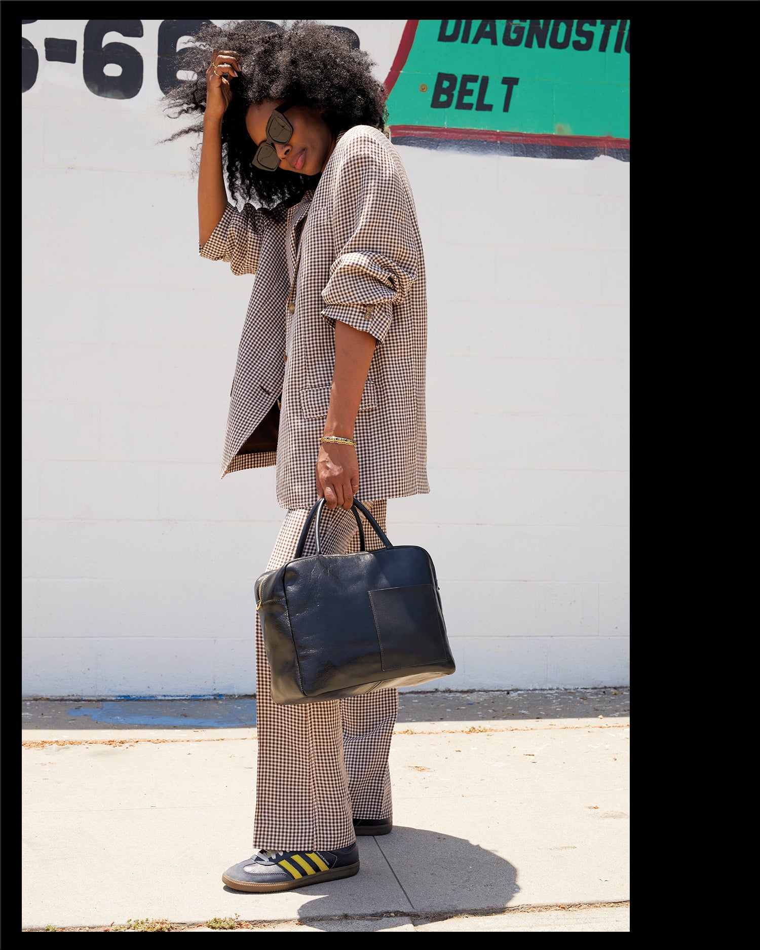 Mecca wearing a plaid suit and carrying the Black Claude.
