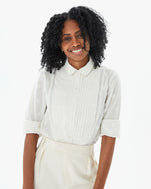 Mecca from the waist up in the Cream Heart Coupé Anette Tuxedo Shirt with white front pleated slacks and her arms at her side