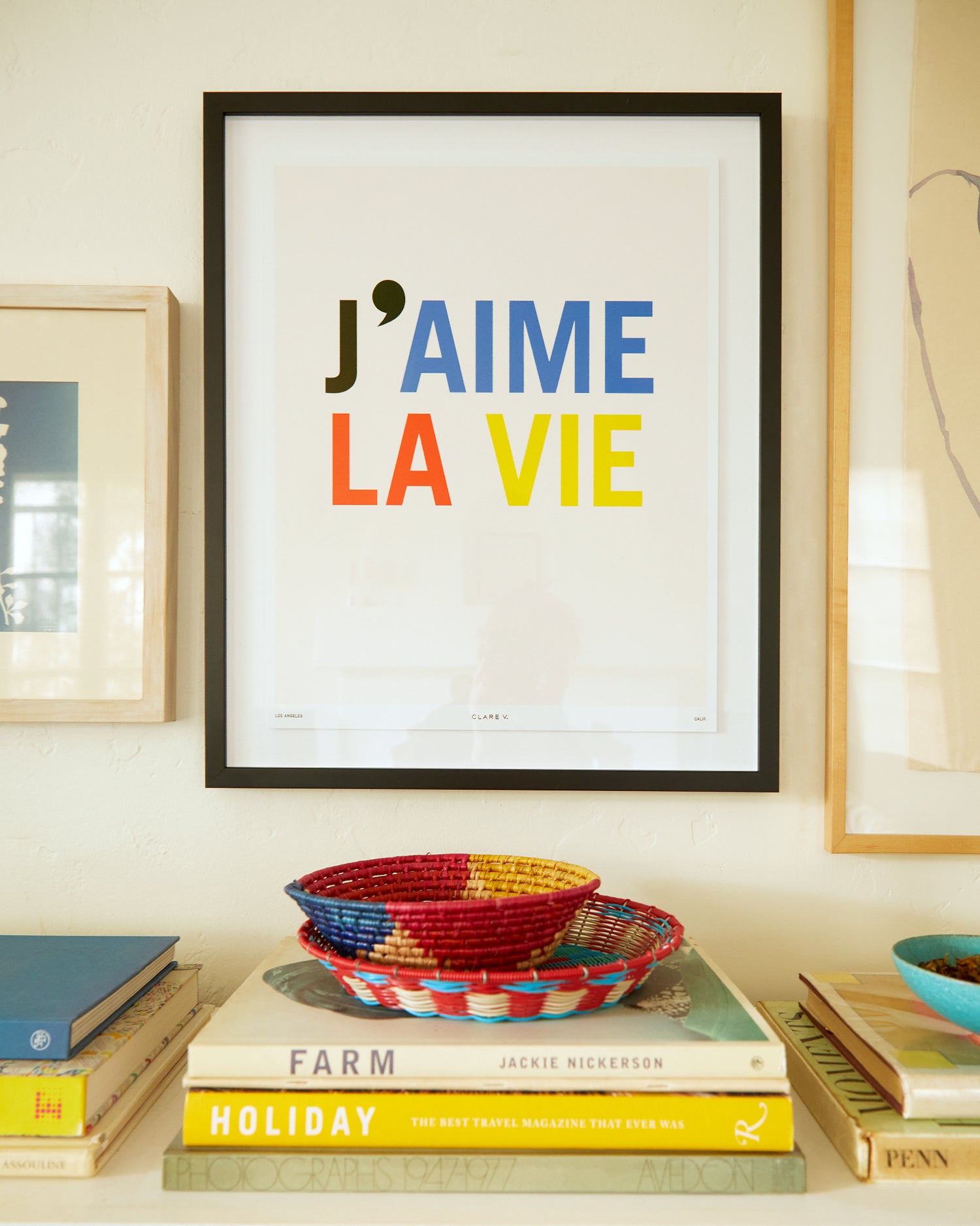 Clare V. x Framebridge J'aime La Vie print sitting above books.