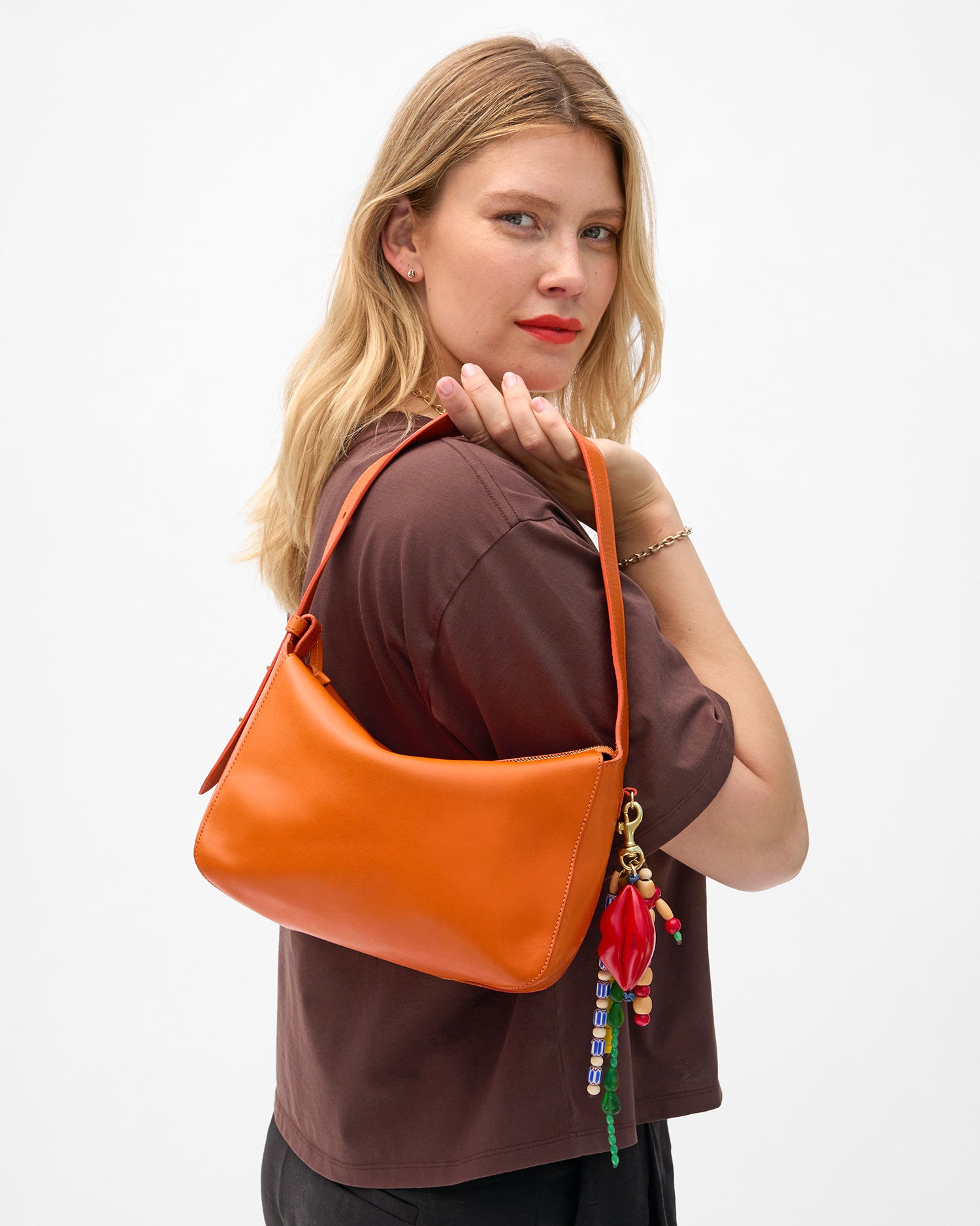 Model carrying the Zucca (orange) Fleurine (with  bag charms attached) as a top handle bag.