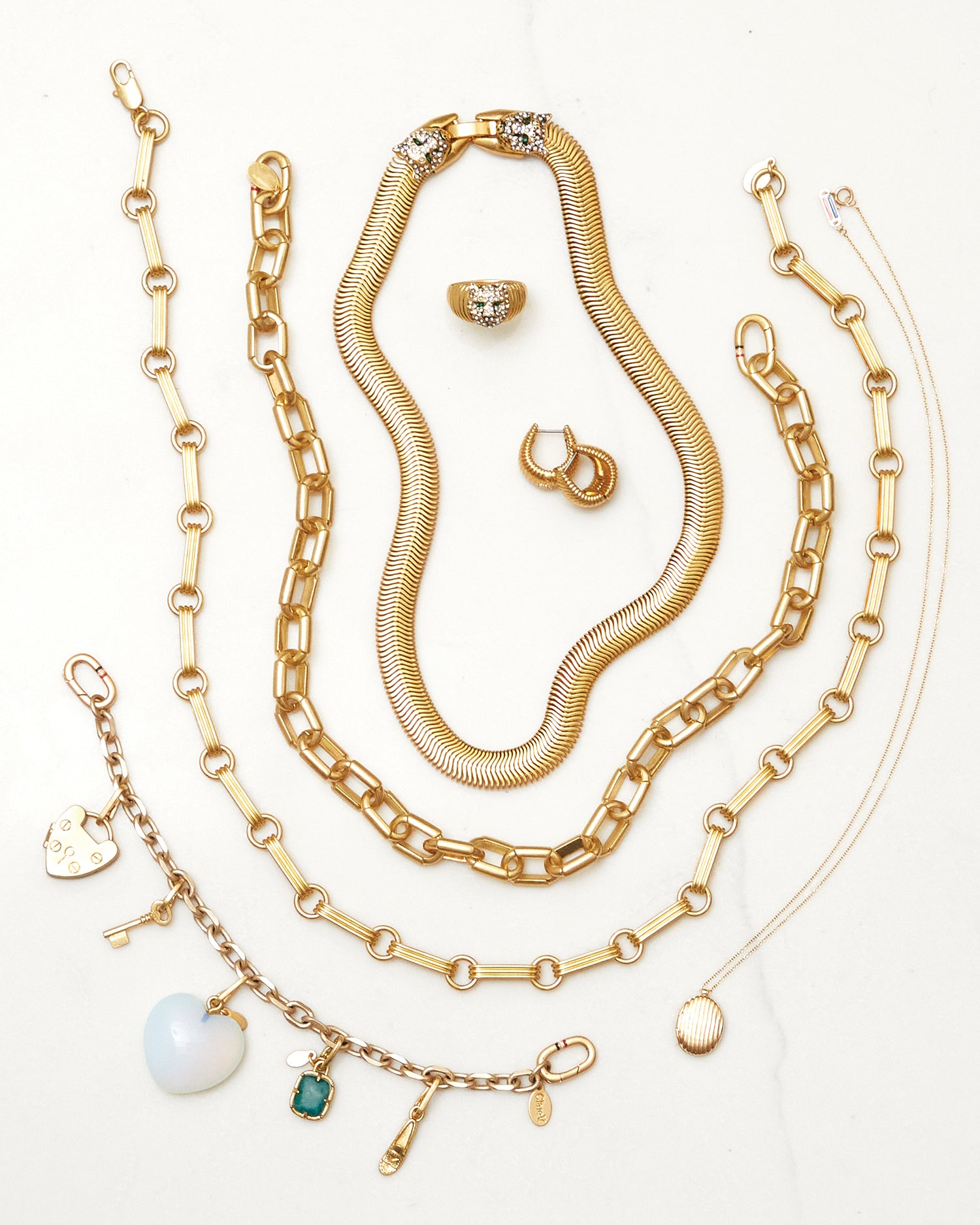 Assortment of Clare V. jewelry. Items featured: Whiskers Signet Ring, Ridge Huggie Earrings, Snake Chain Collar, Le Link Necklace, Charm Bracelet with assorted charms, Ridge Locket Necklace.