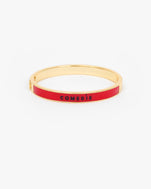 Le Bangle Bracelet with a vibrant red enamel inlay and the word 'COMEDIE' printed in black on the front.
