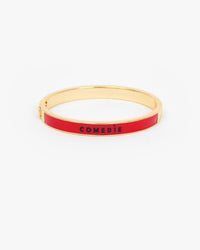 Le Bangle Bracelet with a vibrant red enamel inlay and the word 'COMEDIE' printed in black on the front.