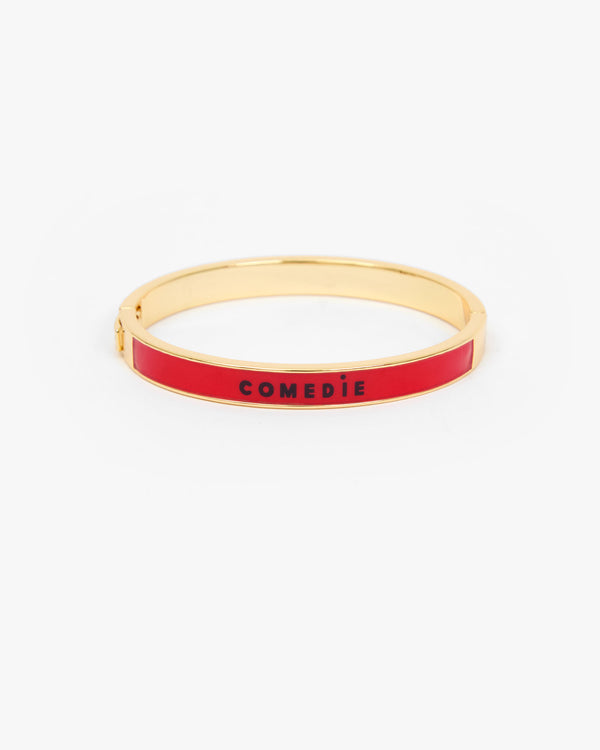 Le Bangle Bracelet with a vibrant red enamel inlay and the word 'COMEDIE' printed in black on the front.