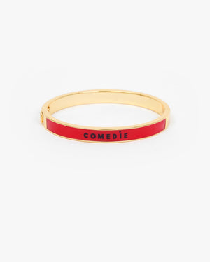 Le Bangle Bracelet with a vibrant red enamel inlay and the word 'COMEDIE' printed in black on the front.