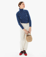 Zoe wearing the Faded Marine Jaguar Le Turtleneck tucked into white jeans. she's carrying the pot de miel with resin top handle