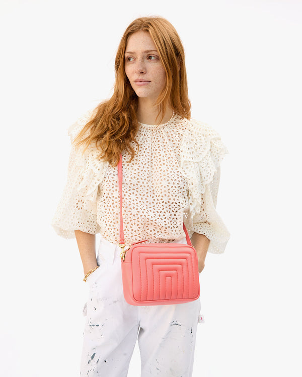 Haley wearing the Bright Coral Channel Quilted Midi Sac crossbody over her all white and cream outfit