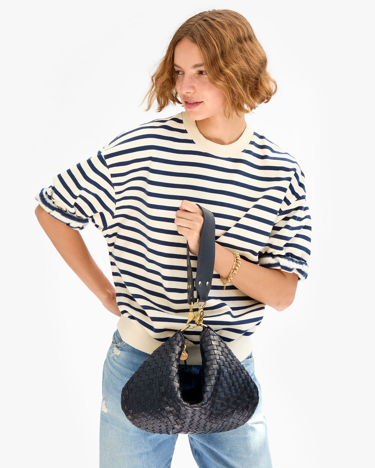 Model carrying the Model wearing the Twilight Diagonal Woven Moyen Messenger as a top handle bag by cinching the bag using the Shoulder Strap.
