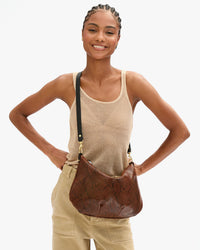 Close up view of Vitoria with Moyen Messenger in Auburn Embossed Python worn as a crossbody