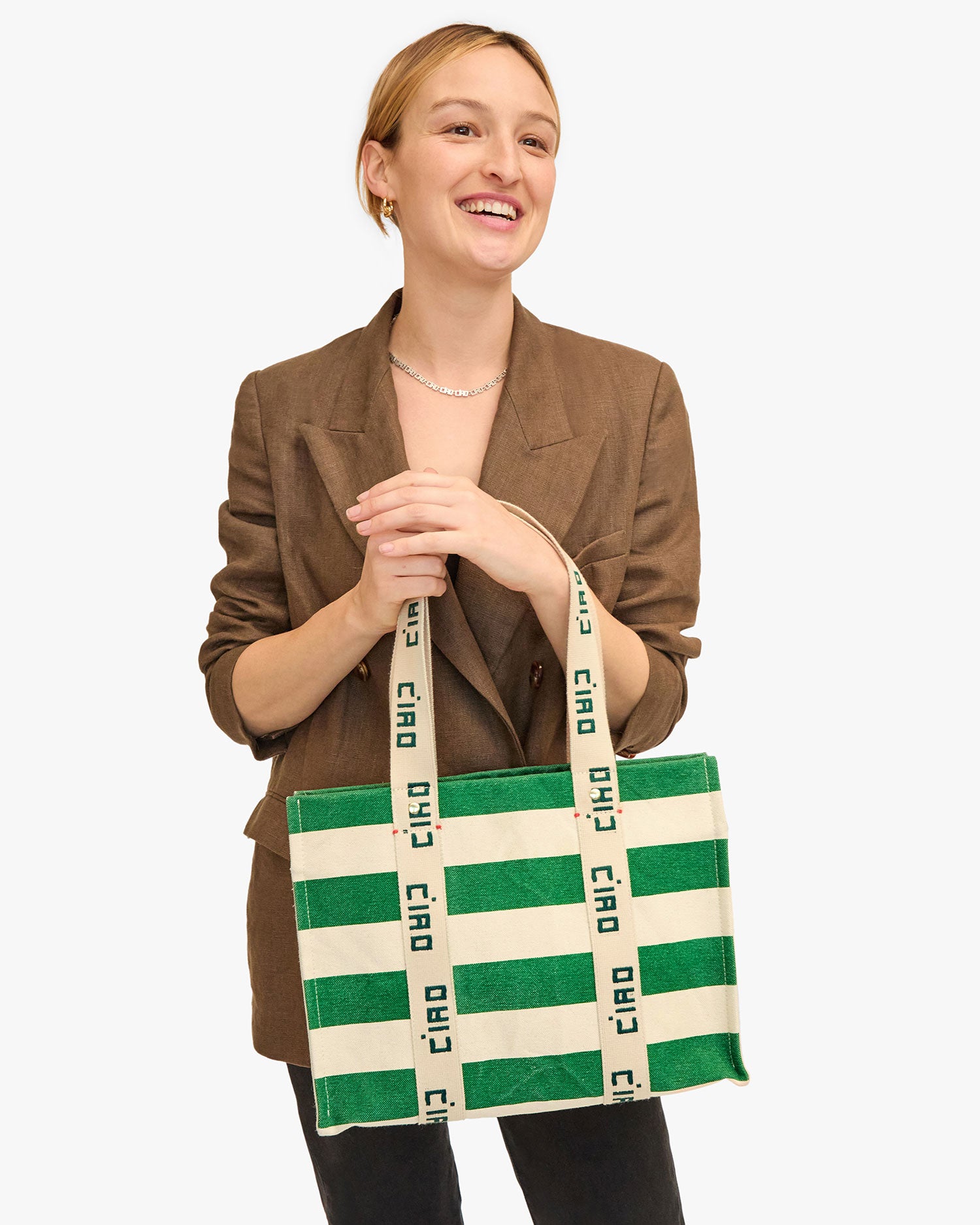 Zoe holds the Noemie Canvas Tote in Palm Green and Natural Stripe in her hands