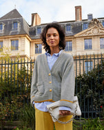 Gabrielle wearing the Oscar Sweater in Cloud over a blue button up shirt and yellow pants