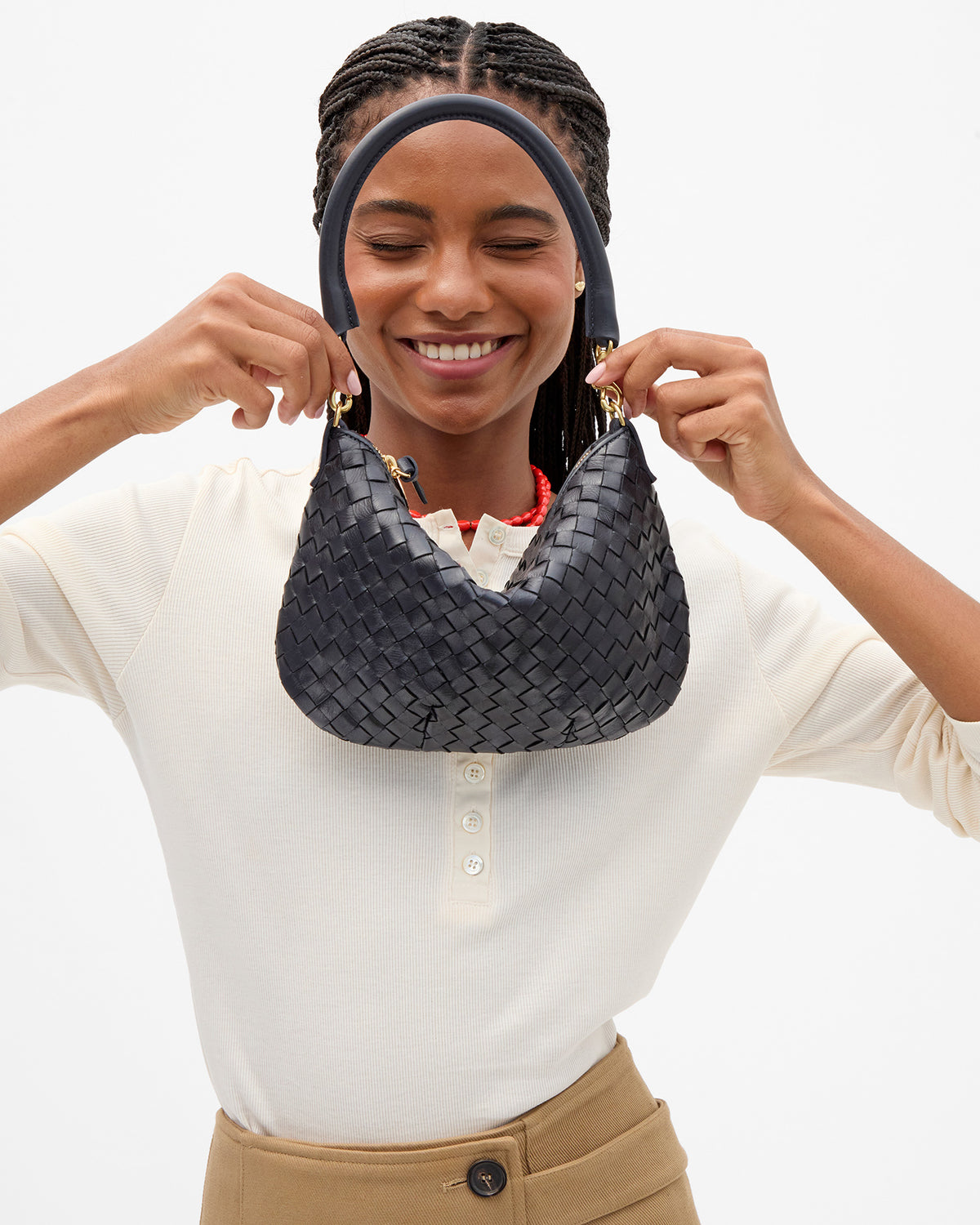 A woman wearing a cream henley shirt and tan pants holding up the Twilight Diagonal Woven Petit Moyen.