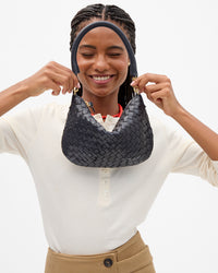 A woman wearing a cream henley shirt and tan pants holding up the Twilight Diagonal Woven Petit Moyen.