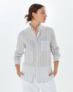 Zoe wearing the cream stripe Single Needle Shirt with white pants and her hands in her pockets