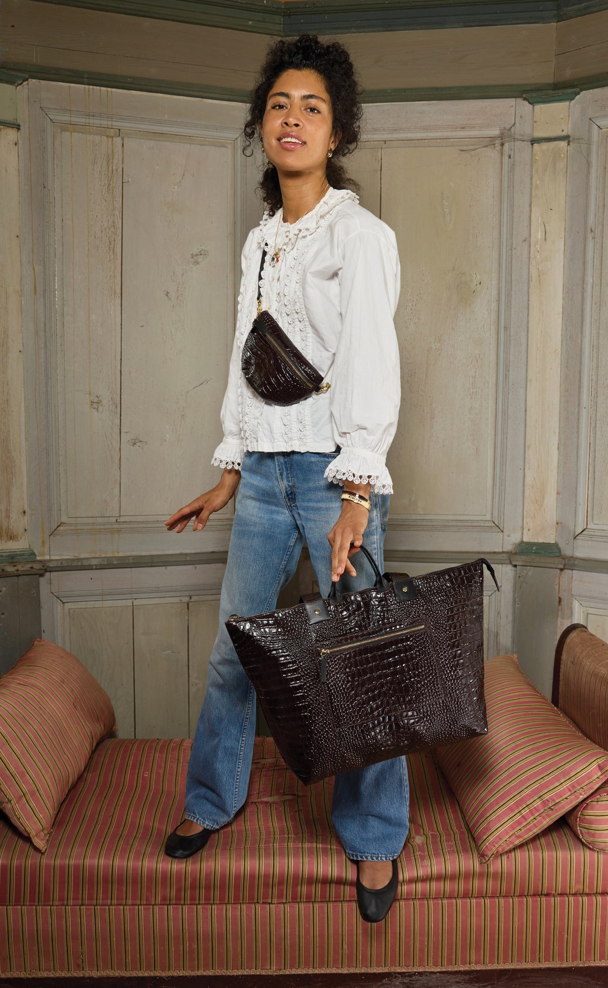 Model holding the Mahogany Embossed Croco w/ Travel Pocket Grand Zip Sac and carrying the matching Petit Fanny across her chest. 