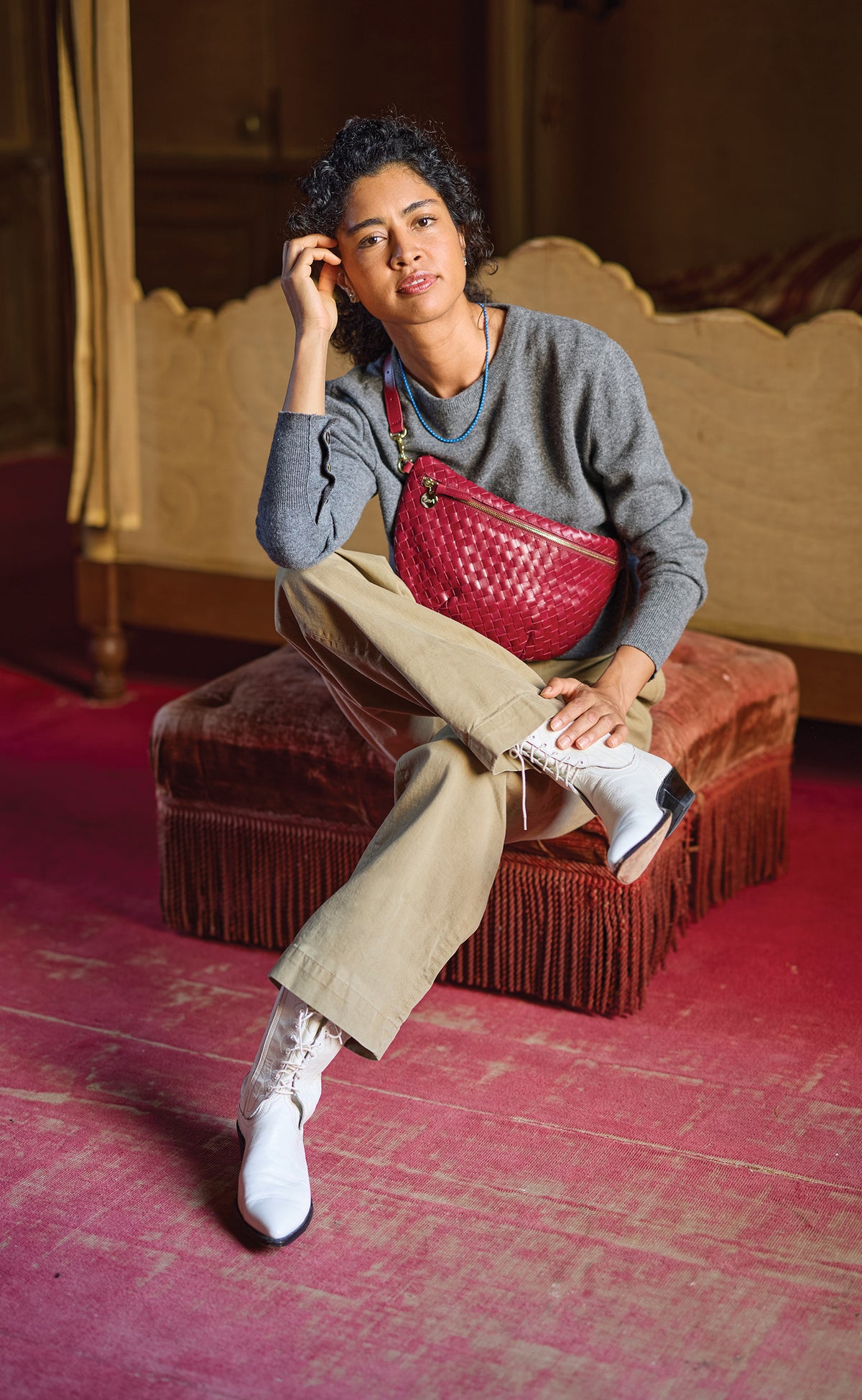 Model sitting down and carrying the Garnet Diagonal Woven Grande Fanny across her chest. 