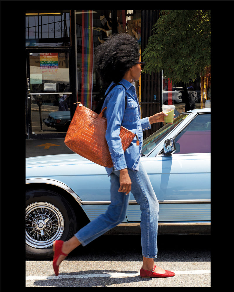 Mecca wearing a denim shirt and pants and carrying the Cuoio Croco Le Zip Sac over her shoulder. 