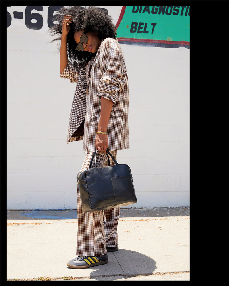 Mecca wearing a plaid suit and carrying the Black Claude.