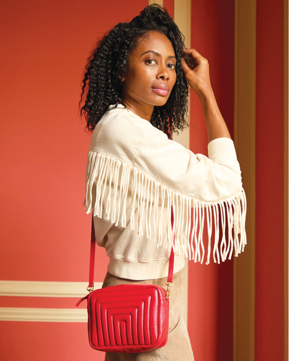 Mecca wearing the Cream Le Drop Fringe Sweatshirt and carrying the Rouge Channel Quilted Midi Sac as a crossbody bag. 