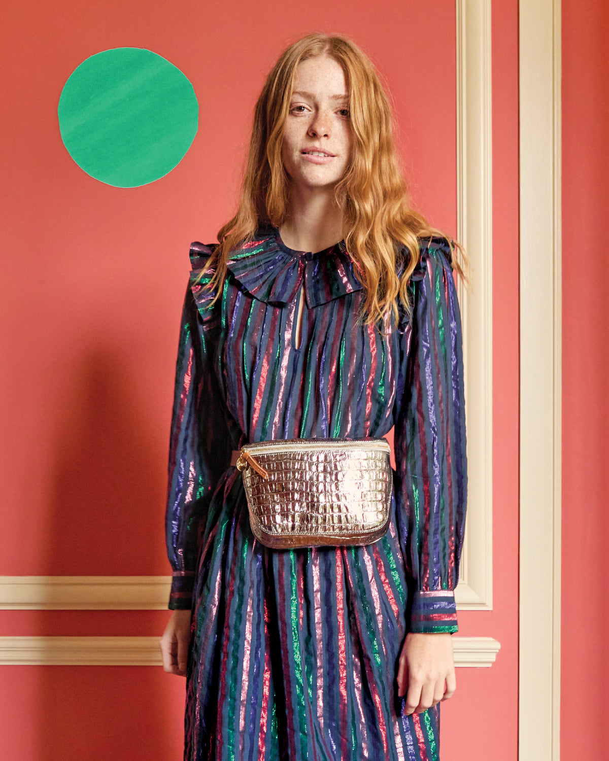 Model wearing Léonie Dress in Multi Lurex/Cotton Stripe and carrying the Silver Metallic Croco Fanny Pack around her waist. 