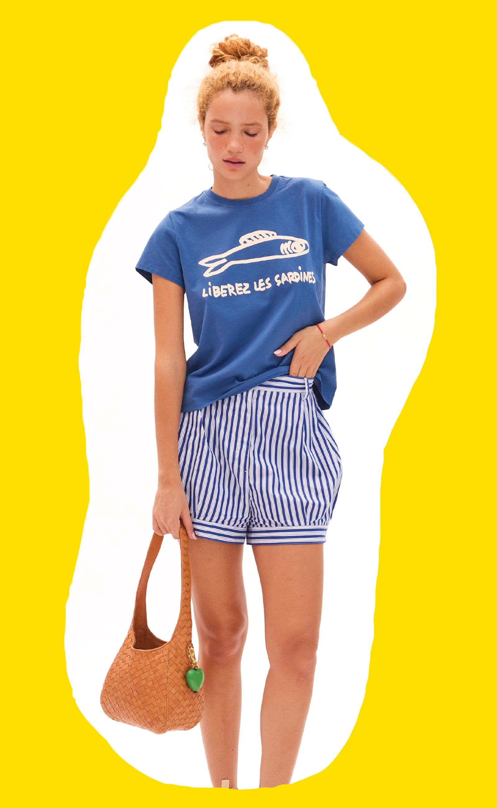 Model wearing the Liberez Les Sardines Classic Tee and carrying the Natural Diagonal Woven Petit Bando with Emerald Heart Fob.