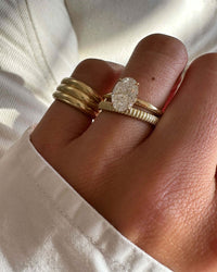 Model wearing the Kinn Studios Annabelle Ring as a wedding band with an assortment of other rings