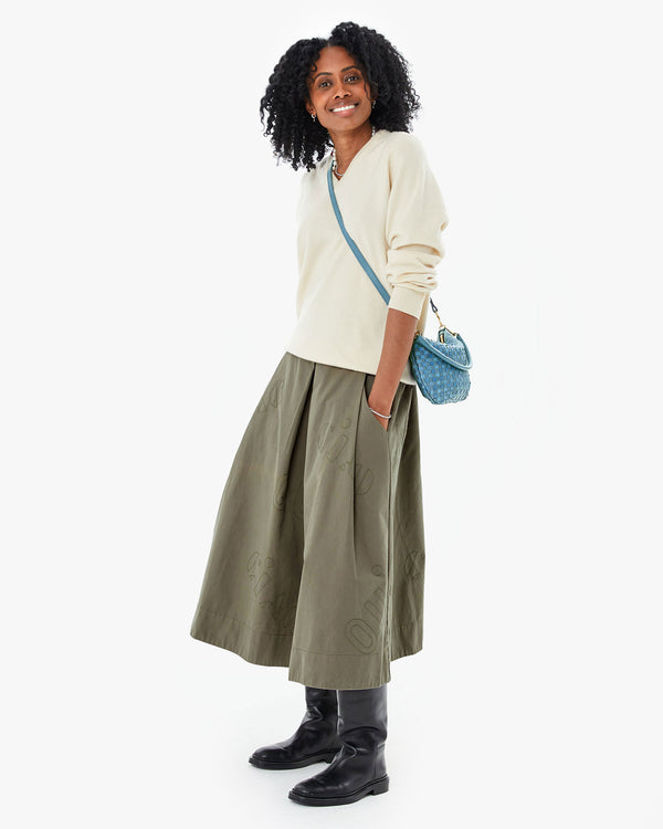 Mecca wearing the Olive Quilted Anais Midi Skirt  with a white sweater and black boots