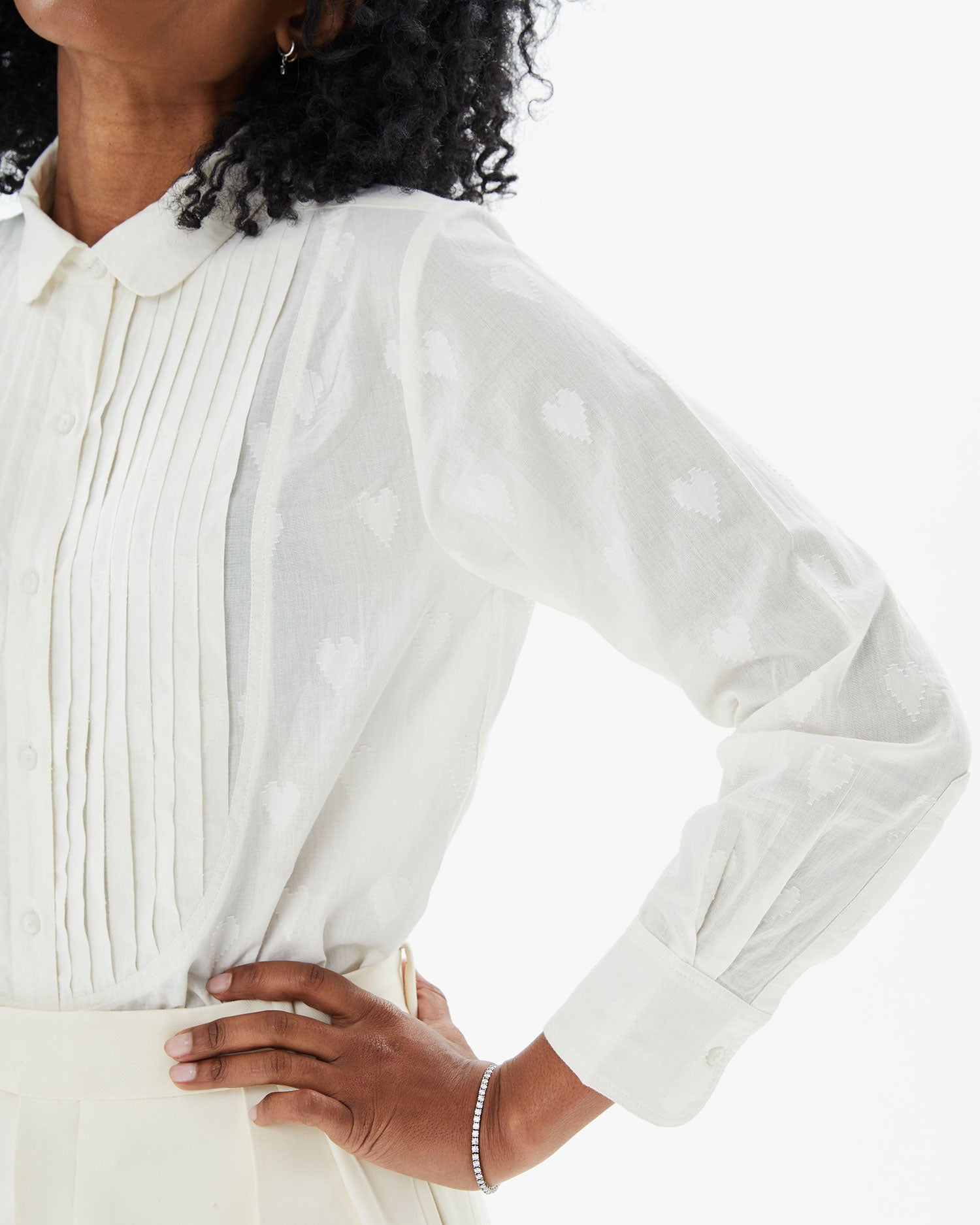 Mecca with her hand on her hips showing the details on the Cream Heart Coupé Anette Tuxedo Shirt