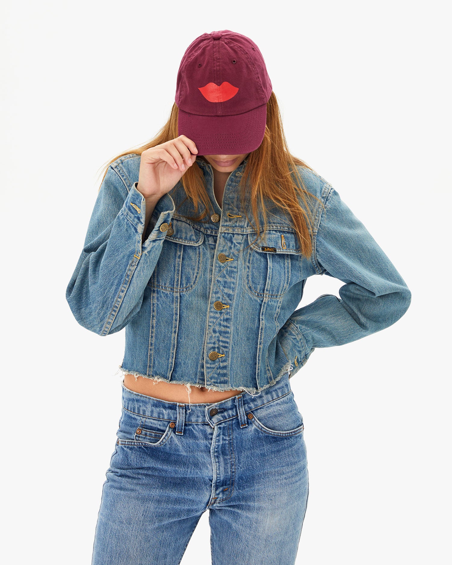 Aurelia touching the brim of the Oxblood with Lips Baseball Hat