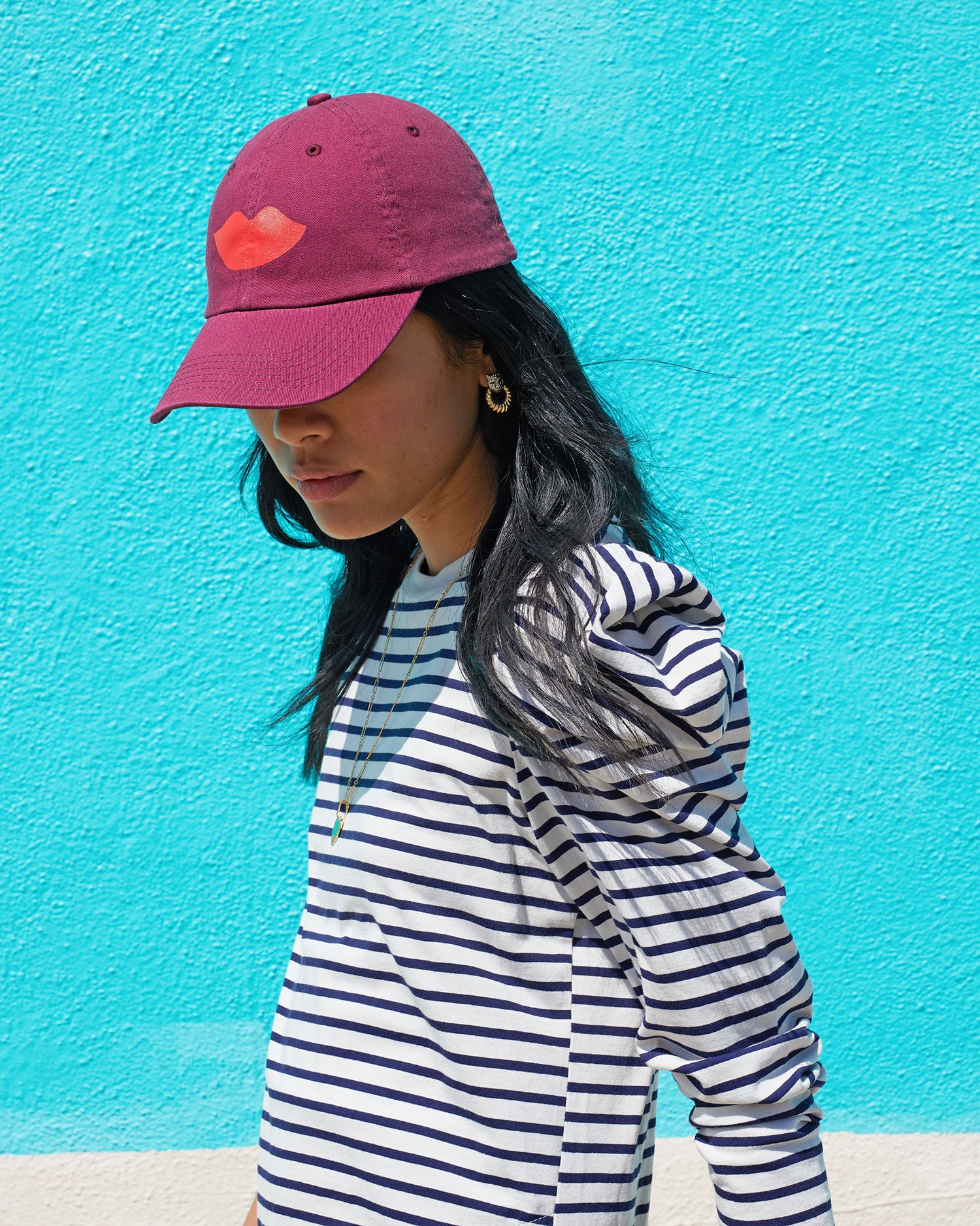 Sandra wearing the Oxblood with Lips Baseball Hat with a striped dress 