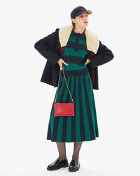 Zoe wearing the Heloise skirt and polo with a coat and the Navy Corduroy Ciao Baseball Hat. her hands are on her hips