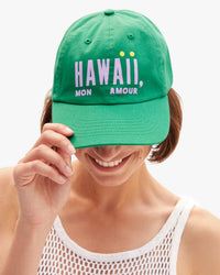 Model wearing the Hawaii Mon Amour Baseball Hat and holding the visor part of the hat down. 