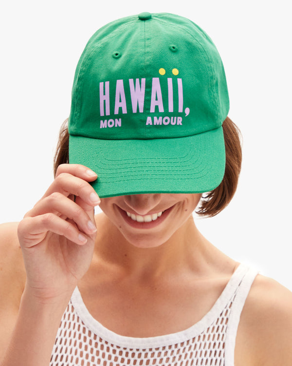 Model wearing the Hawaii Mon Amour Baseball Hat and holding the visor part of the hat down. 
