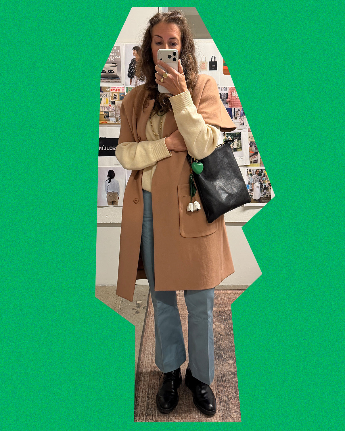 Clare wearing a brown coat with jeans and carrying the Black Petit Caviar Foldover Clutch with Tabs as a shoulder bag.