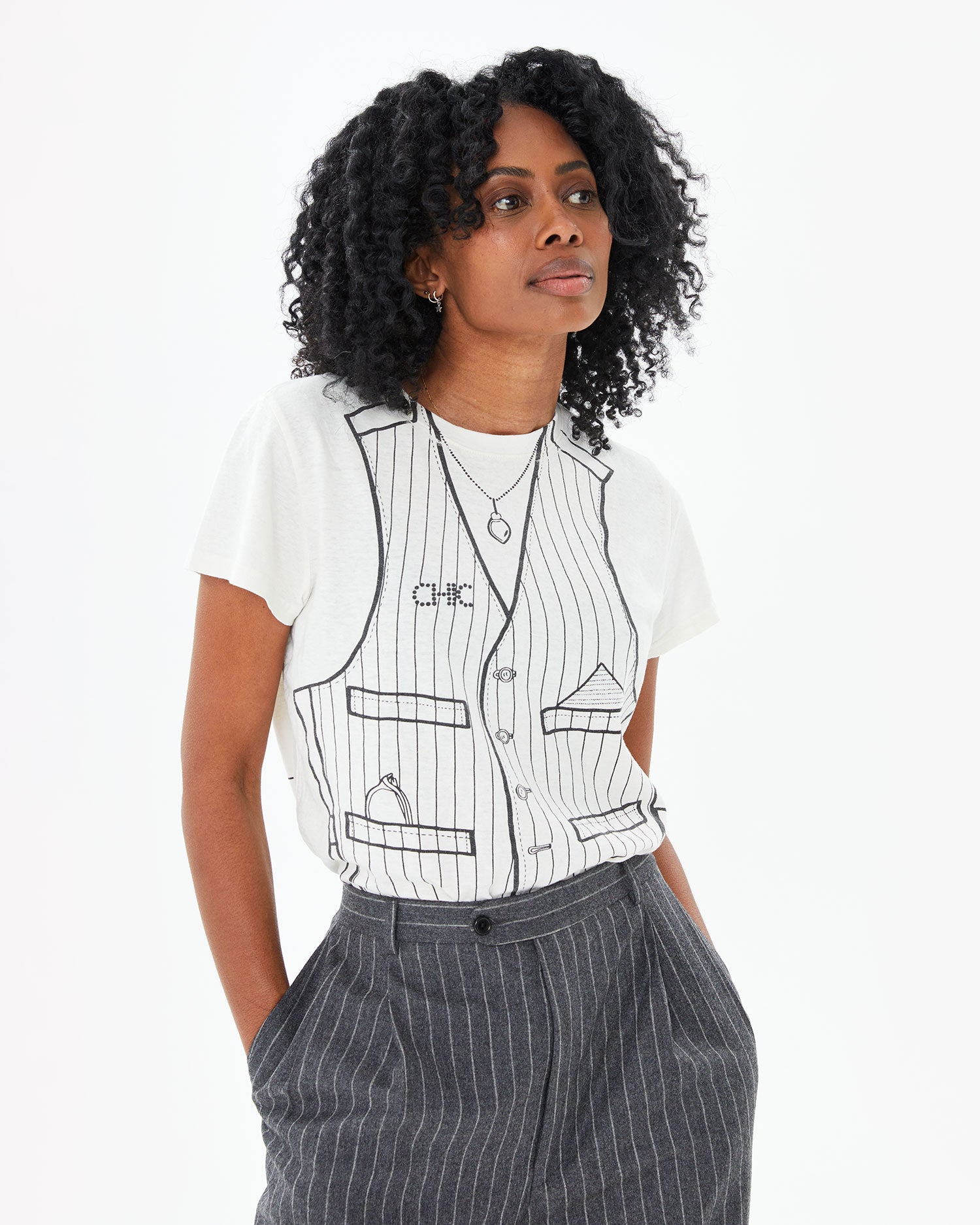 Mecca wearing the Cream Trompe l’oeil Vest Classic Tee tucked in to suit pants 