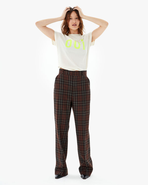 Zoe touching her hair in the Cream Oui Classic Tee tucked in to brown plaid pants