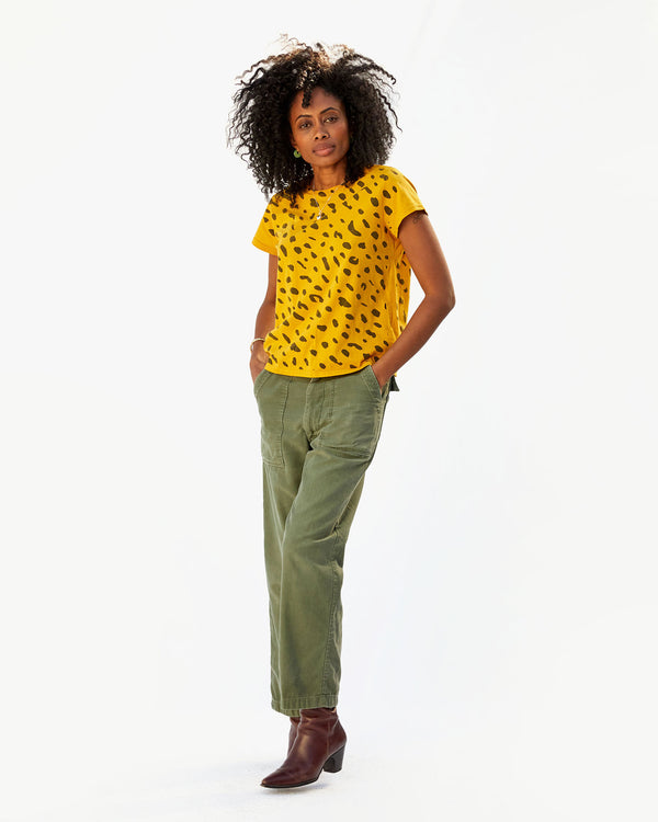 Mecca wearing army pants and brown boots with the Marigold Jaguar Classic Tee and her hands in her pockets