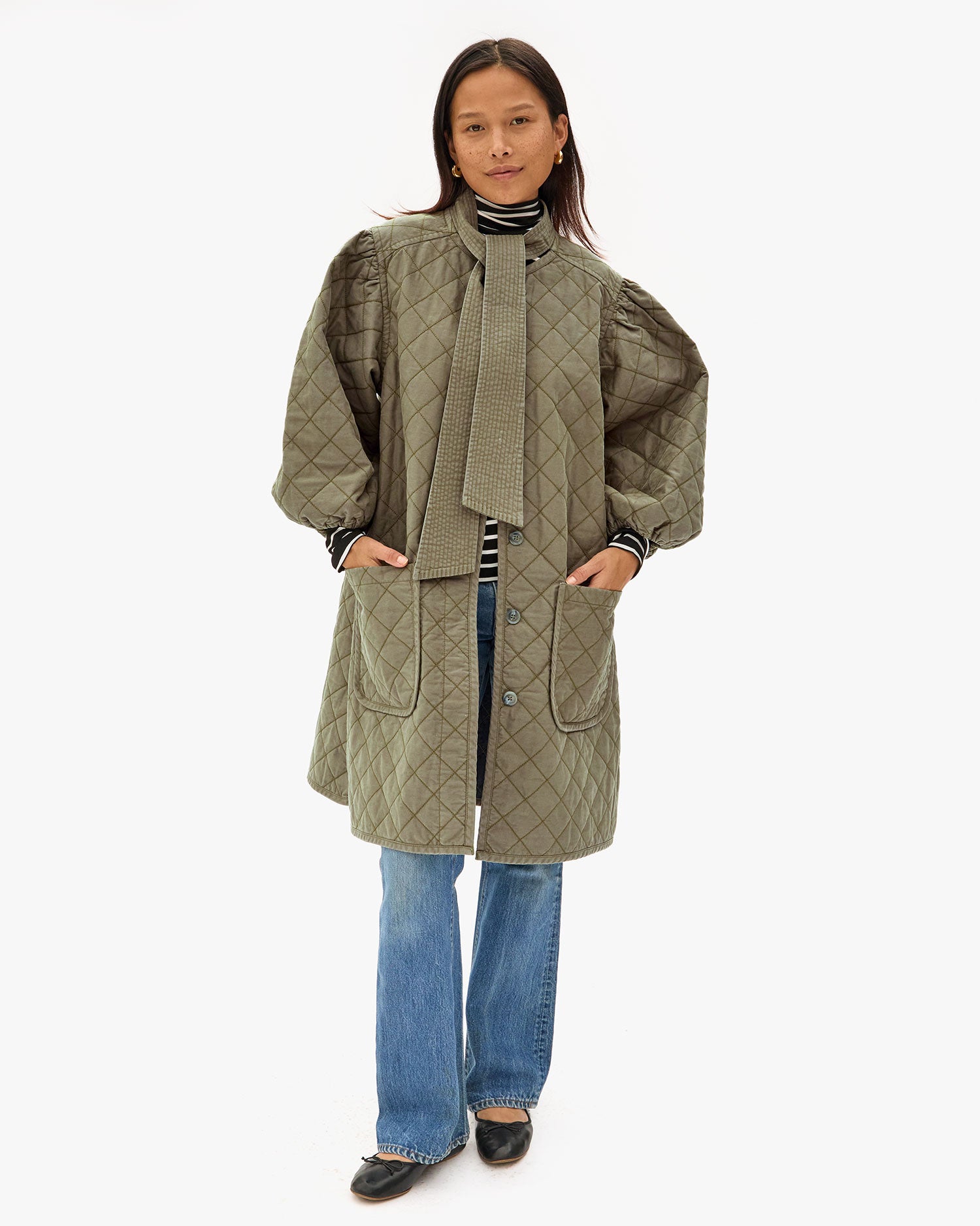Maly wearing the Olive Quilted Clemence Car Coat and tucking her hands in the front pockets. 