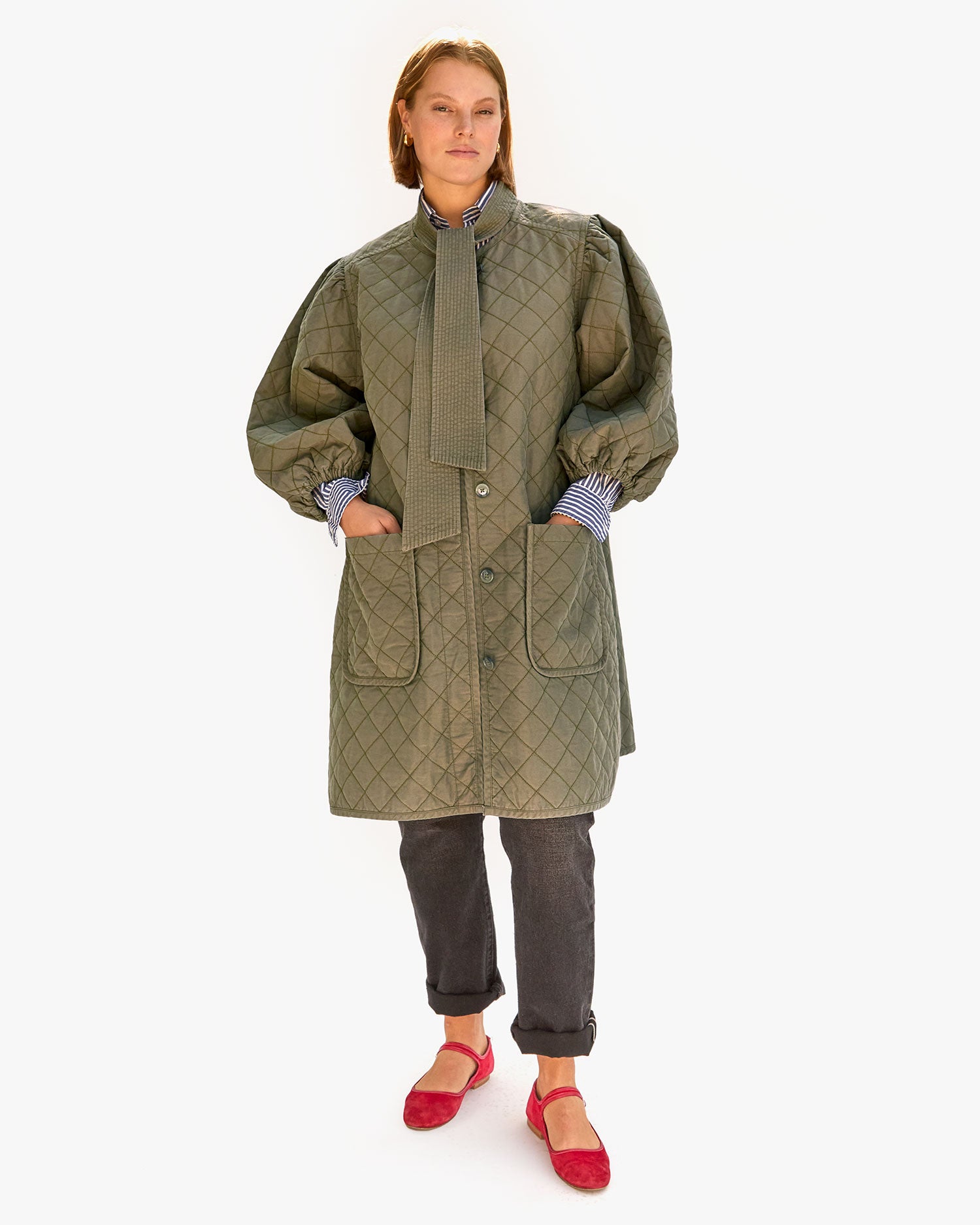 Sonnie wearing the Olive Quilted Clemence Car Coat and tucking her hands in the pockets. 