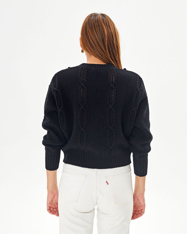 back view of aurelia in the Black with red and navy chains Drop Shoulder Sweater and white jeans