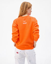 Back of the ÇA SUFFIT! sweatshirt in bright neon orange on Haley