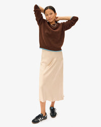 Maly in the Chocolate Elsa Sweater, tan midi length skirt with black and white sneakers and a pearl necklace