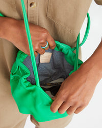 Mecca shows the interior of the Parrot Green Emma crossbody with an assortment of items that fit inside