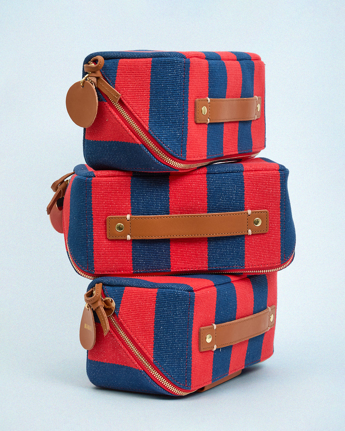 Three Poppy and French Blue Canvas Stripe Vacances stacked on top of each other. 