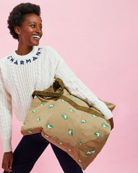 Model wearing the Cream w/ Navy Charmant Fisherman Sweater with black pants. she's holding the khaki canvas giant trop