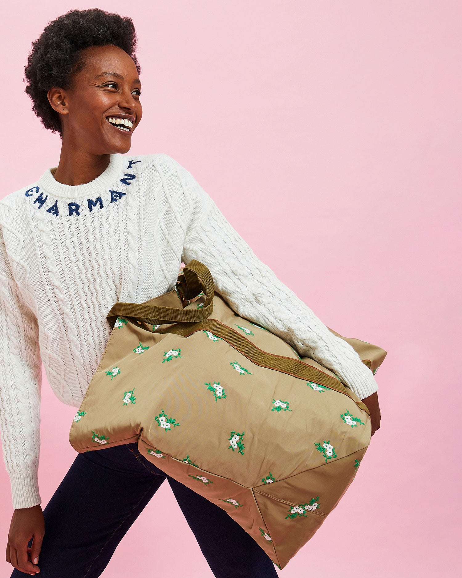 Model wearing the Cream w/ Navy Charmant Fisherman Sweater with black pants. she's holding the khaki canvas giant trop