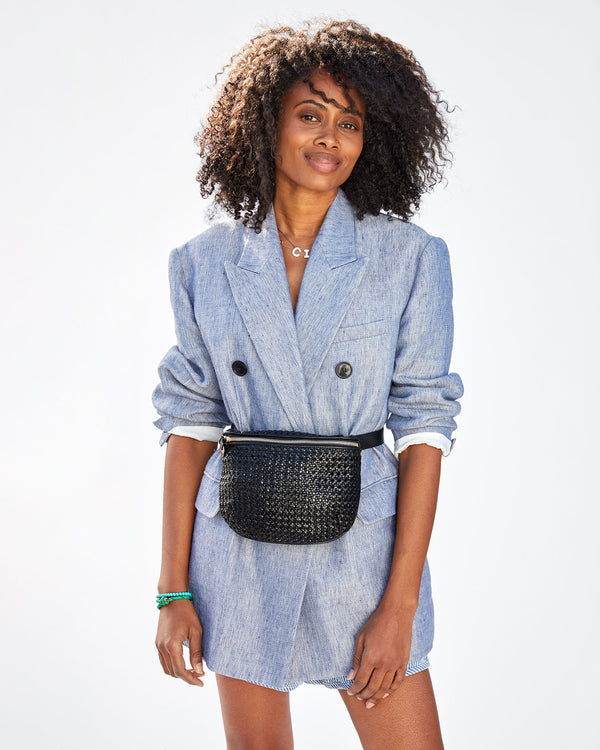 Mecca  wearing the Black Rattan Fanny Pack around her waist over a chambray blazer