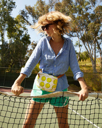 Lou wears the Natural with Tennis Balls Fanny Pack belted at her waist
