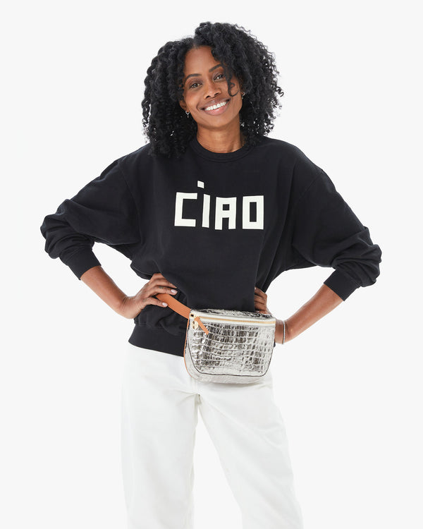 Mecca with her hands on her hips in the Black Ciao Oversized sweatshirt, white pants and the Silver Metallic Croco Fanny Pack around her waist