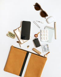 Camel with Black and Cream Stripes Flat Clutch with Tabs showing the items that fit inside it. There are sunglasses, airpods, a pen, a small notepad, gum, an advil to-go pack, lipstick, a key, an iphone, some cash and a coin clutch